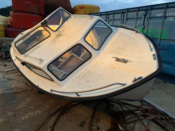 En gammel fritidsbåt som ligger skjevt på bakken